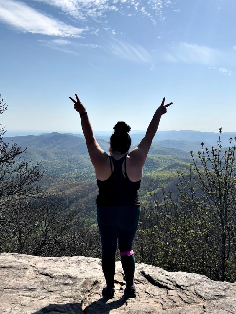 The back of a woman standing on top of Blood Mountain.