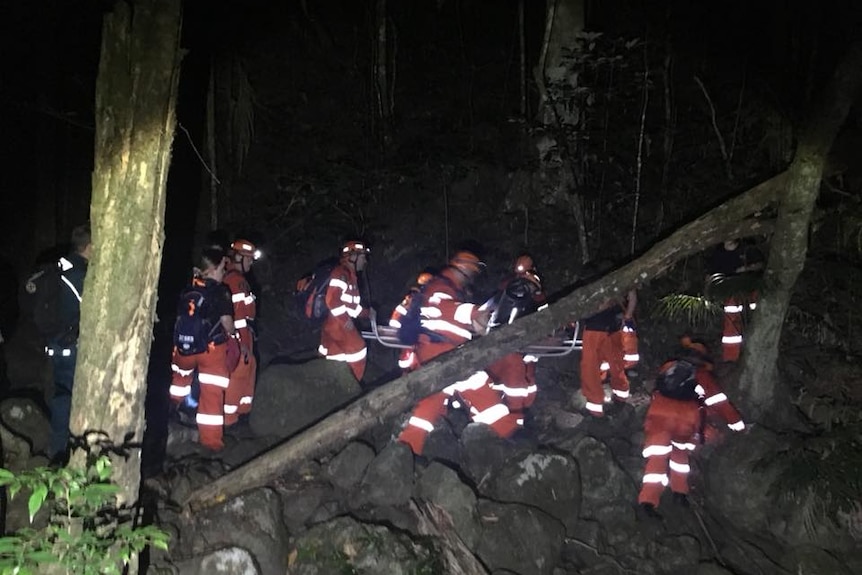 A group of SES lifeguards dressed in orange carry out a rescue in the dark