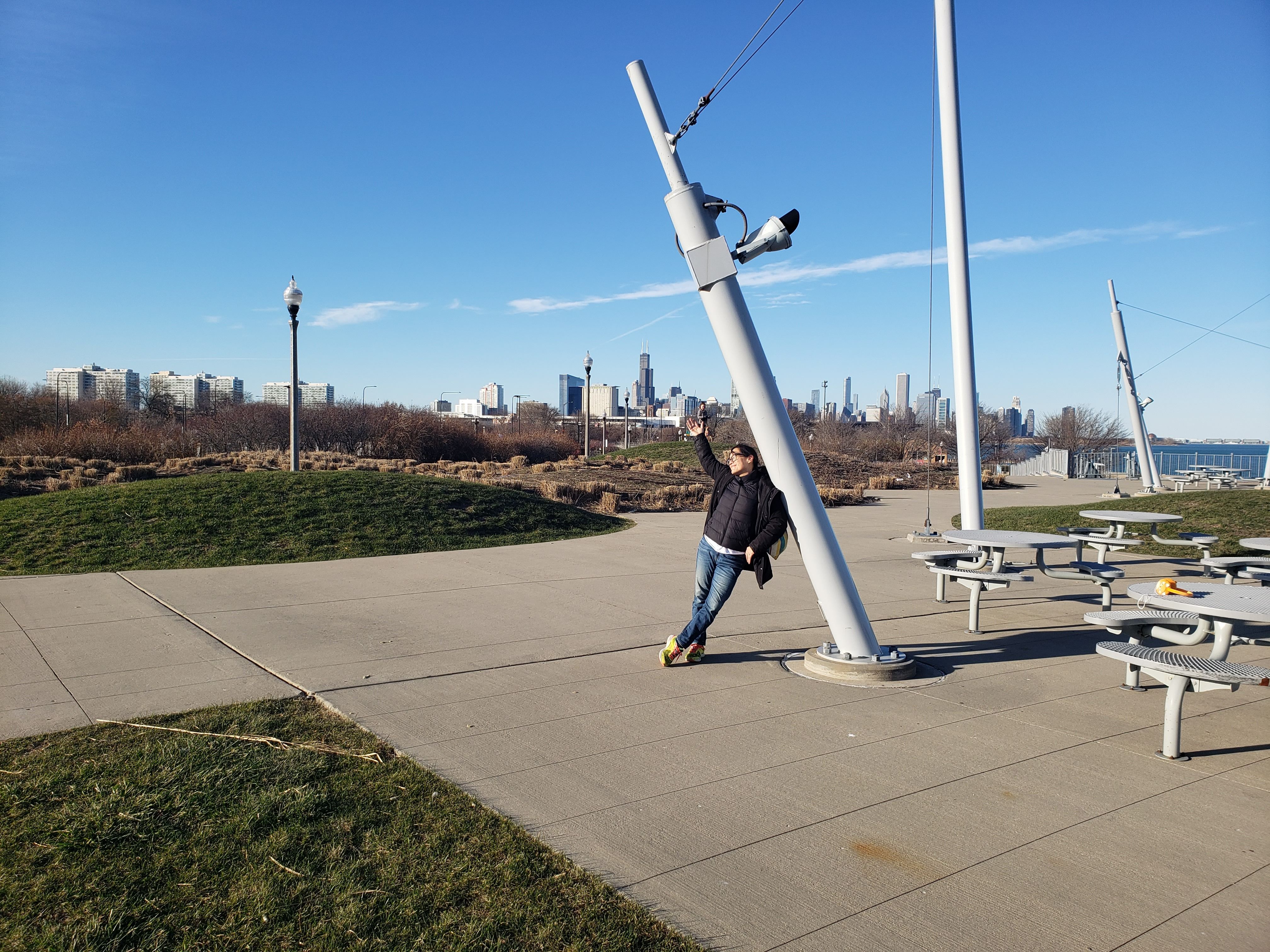 Photo of a woman leaning against a lamp post with the city skyline in the background.