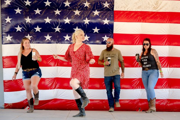 Festival-goers line dance during Five Winds Country Music...
